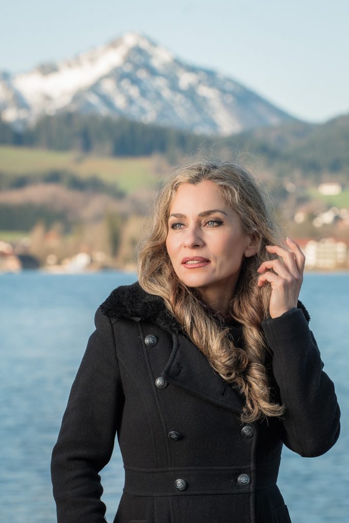 Portraitfotografie am Tegernsee – Frau im schwarzen Mantel mit Alpenkulisse